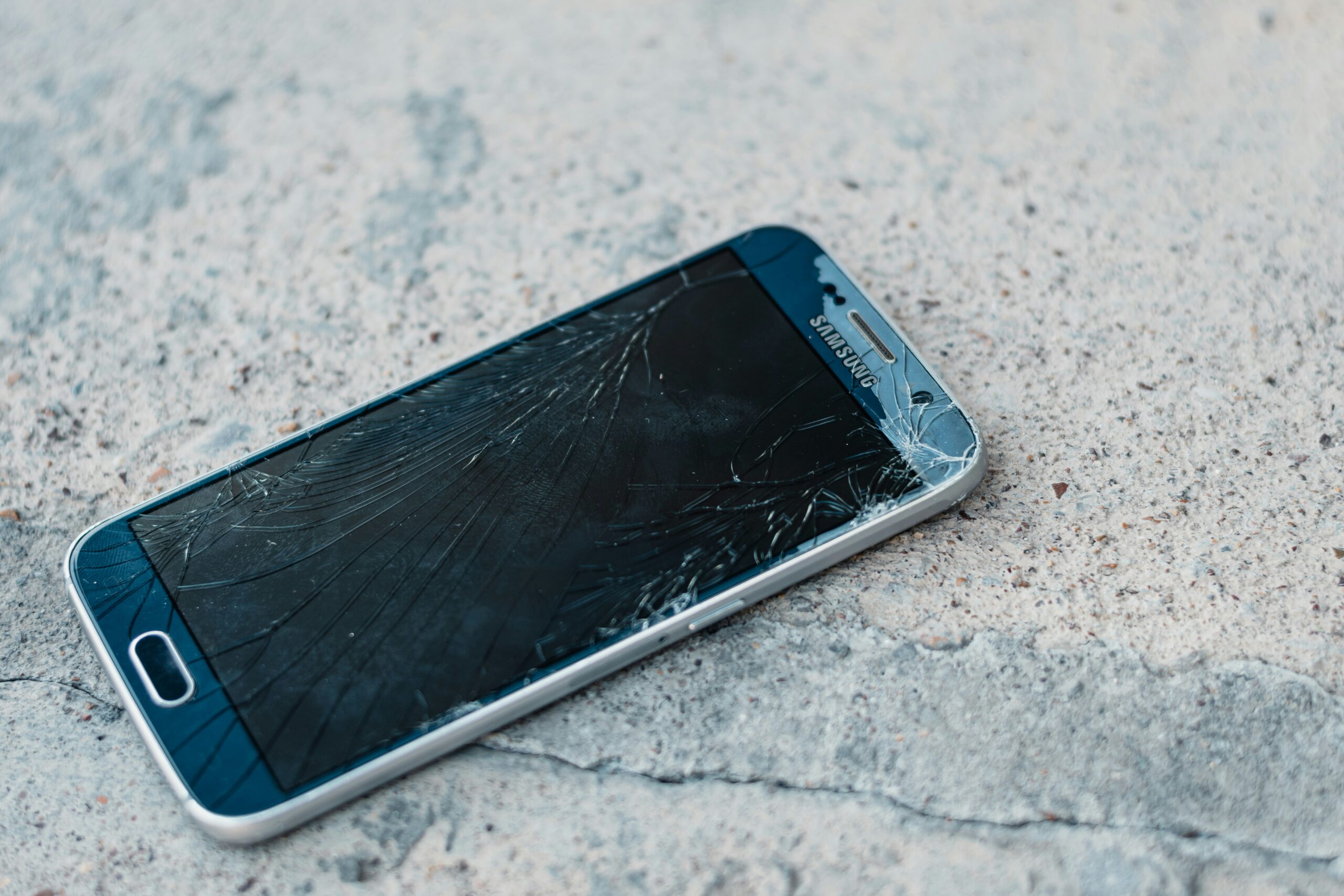 shattered smartphone screen on pavement - Samsung Galaxy S6 with shattered screen